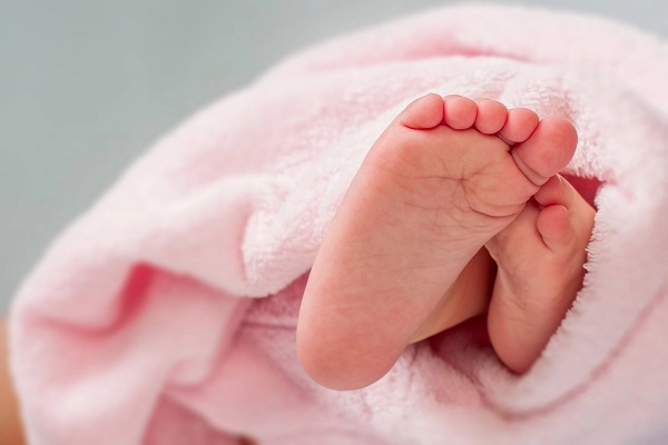 testimonial-birth-jasmine Baby feet poke out from cozy pink blanket.