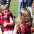 Twopreschoolgirlsinlifejacketsplayinaninflatableraftonthegrassnearthevolunteertent