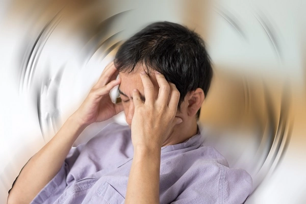 Photo illustration of a dizzy man with his hands on his head.